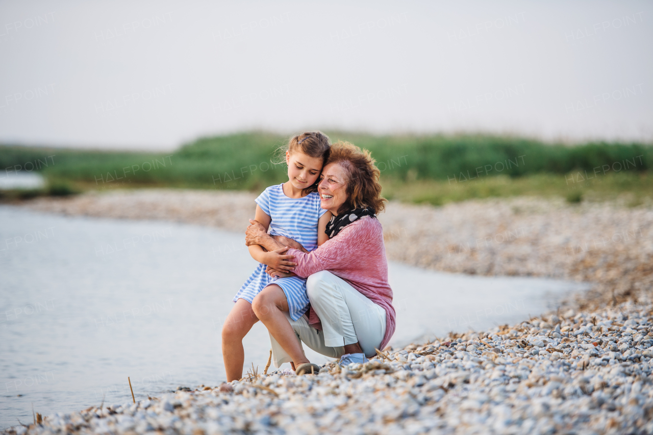 A small girl with grandmother on a holiday by the lake, talking.