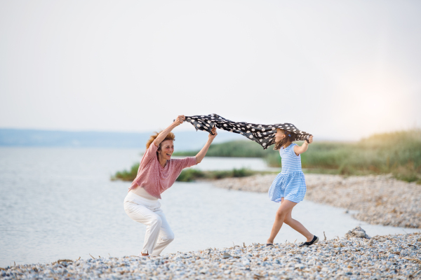 A small girl with grandmother on a holiday by the lake, having fun.