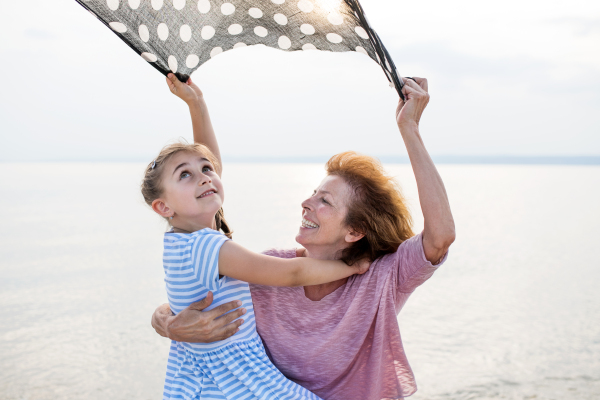 A small girl with grandmother on a holiday by the lake, having fun.