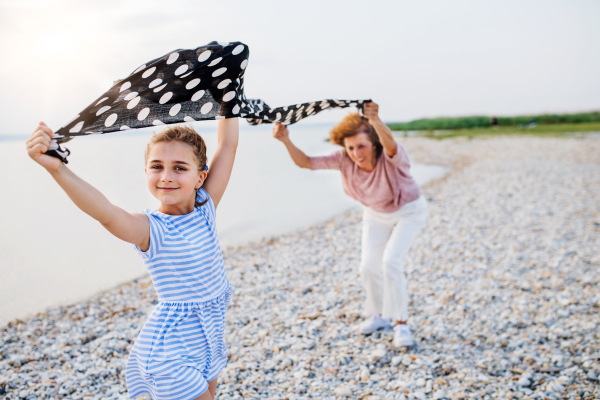 A small girl with grandmother on a holiday by the lake, having fun.