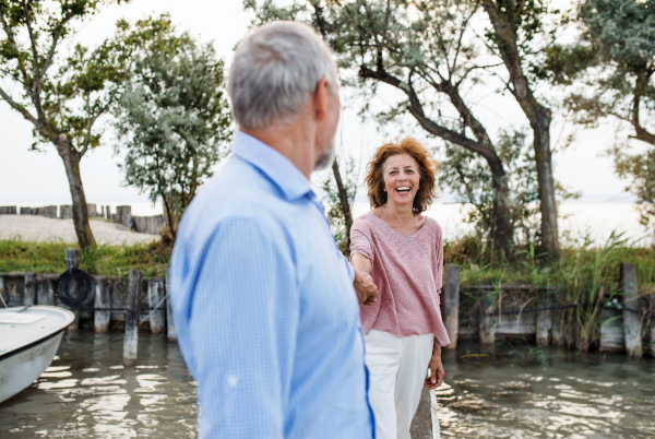 A senior couple on a holiday walking by the lake. Copy space.