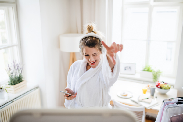 Young woman with headphones indoors at home in the morning, listening to music.