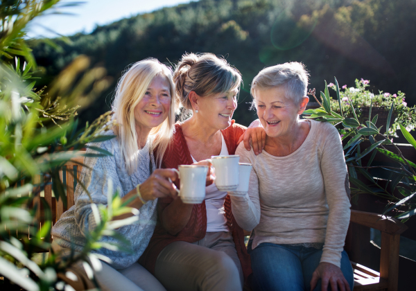 Group of senior women friends sitting outdoors on terrace, resting.