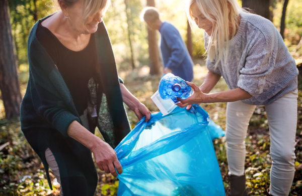 Group of senior women friends picking up litter outdoors in forest, a plogging concept.