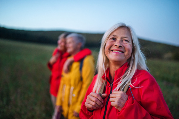 Happy senior women friends on walk outdoors in nature at dusk.