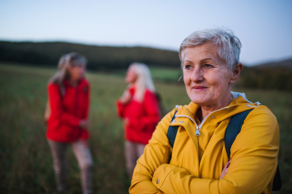 Happy senior women friends on walk outdoors in nature at dusk.