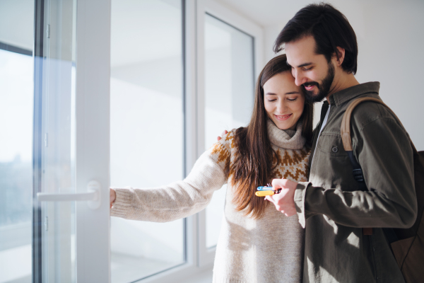 Happy young couple with keys moving in new flat, new home and relocation concept.