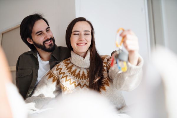 Happy young couple with keys moving in new flat, new home and relocation concept.