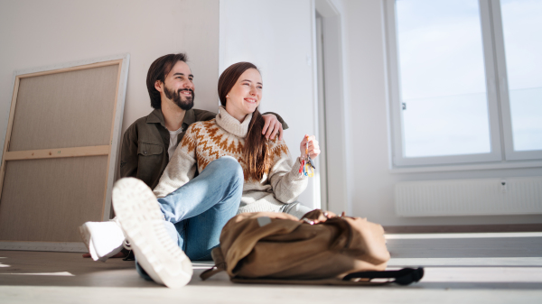 Happy young couple with keys moving in new flat, new home and relocation concept.