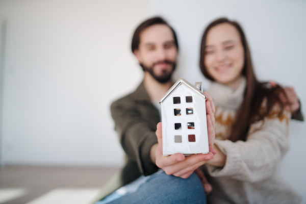 Happy young couple owners holding house model, moving in, new home and relocation concept.