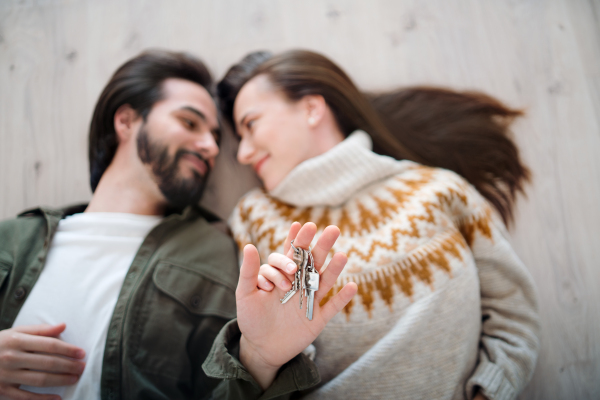 Top view of happy young couple on floor with keys moving in new flat, new home and relocation concept.