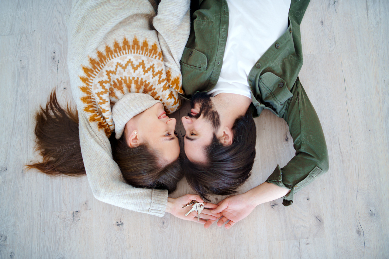 Top view of happy young couple on floor with keys moving in new flat, new home and relocation concept.