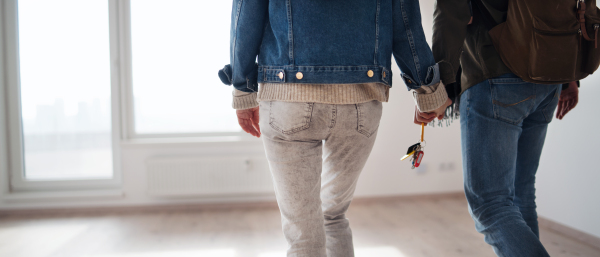 Midsection of unrecognizable young couple with keys moving in new flat, new home and relocation concept.