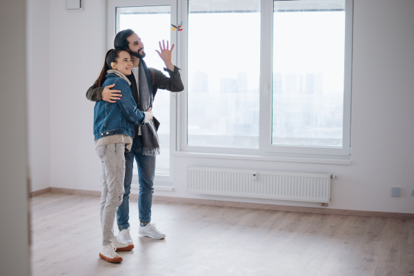 Happy young couple owners hugging in new flat, moving in, new home and relocation concept.