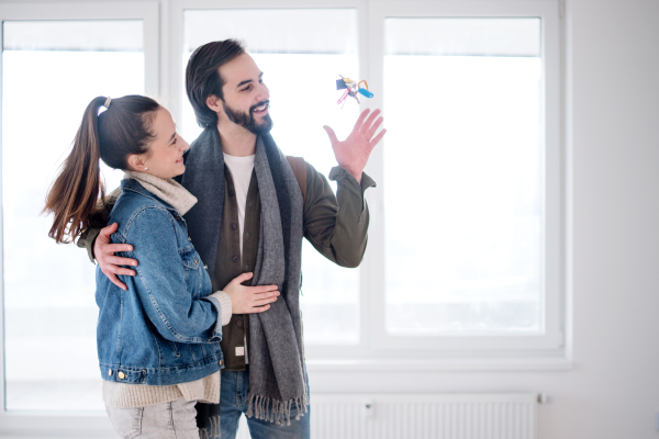 Happy young couple owners throwing keys in new flat, moving in, new home and relocation concept.