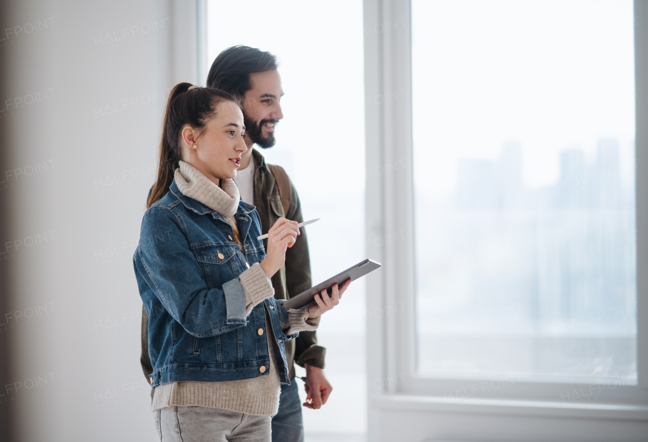 Happy young couple with tablet moving and planning in new flat, new home and relocation concept.