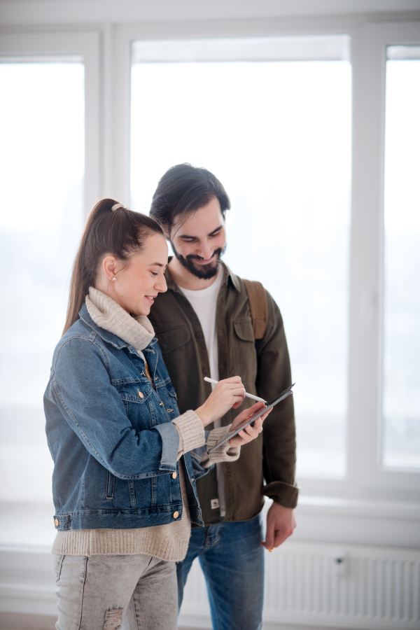 Happy young couple with tablet moving and planning in new flat, new home and relocation concept.