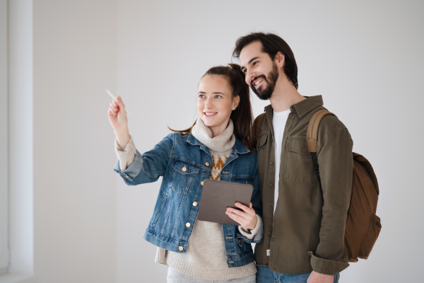 Happy young couple with tablet moving and planning in new flat, new home and relocation concept.