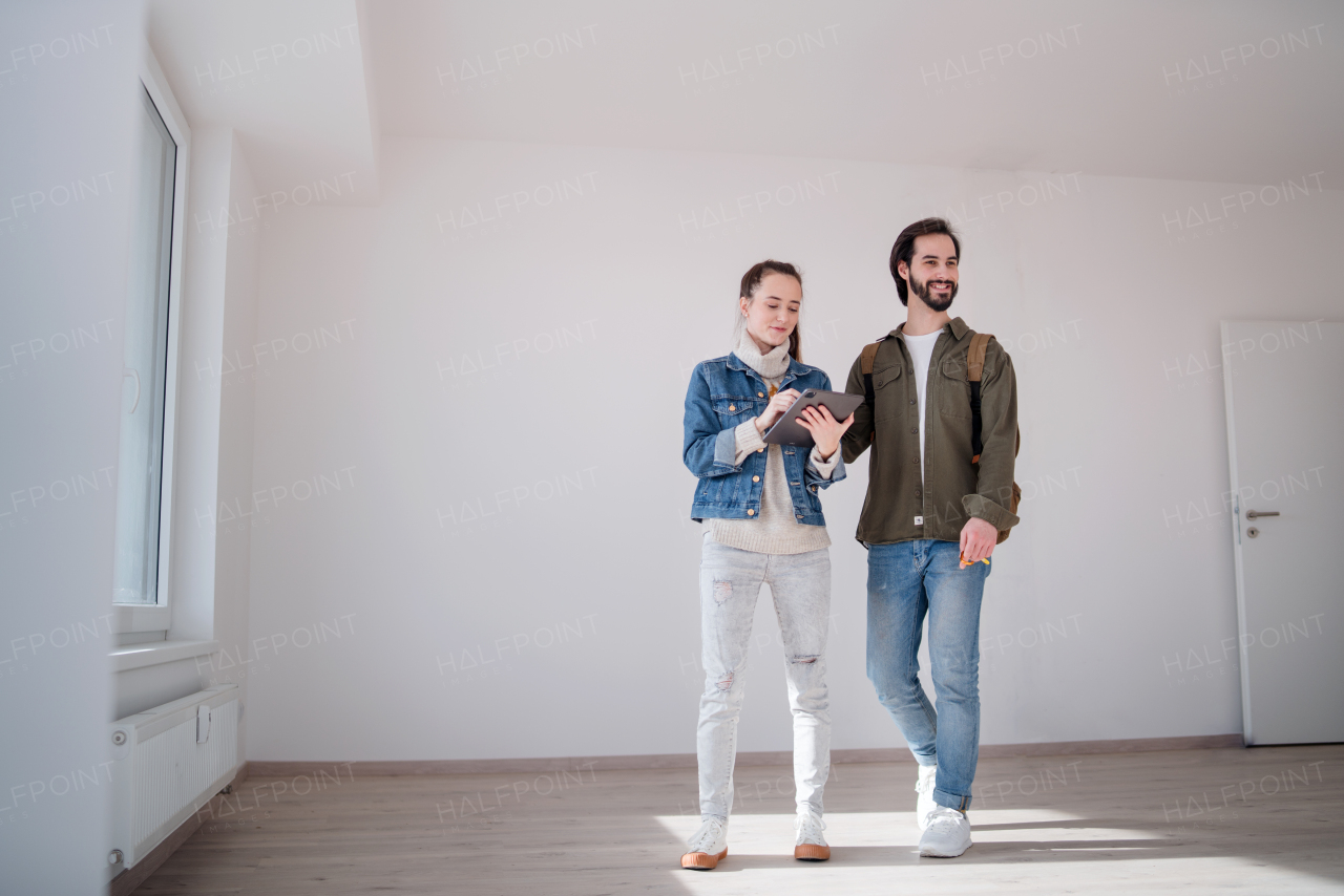 Happy young couple with tablet moving and planning in new flat, new home and relocation concept.