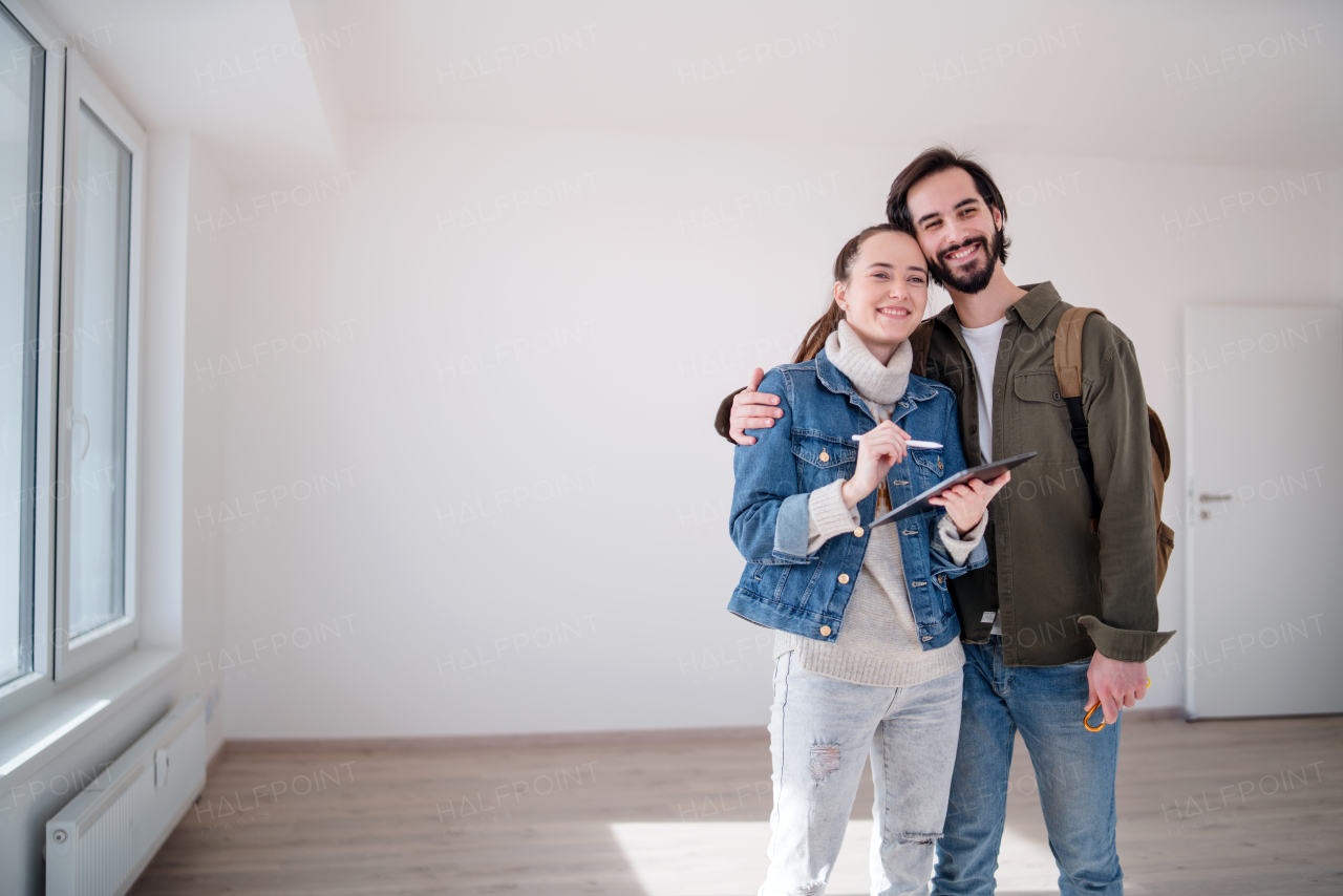 Happy young couple with tablet moving and planning in new flat, new home and relocation concept.