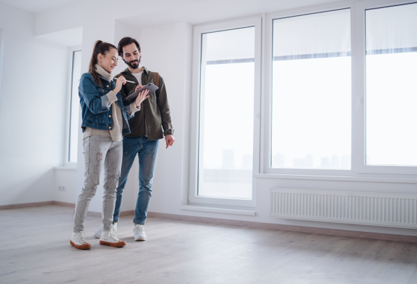 Happy young couple with tablet moving and planning in new flat, new home and relocation concept.