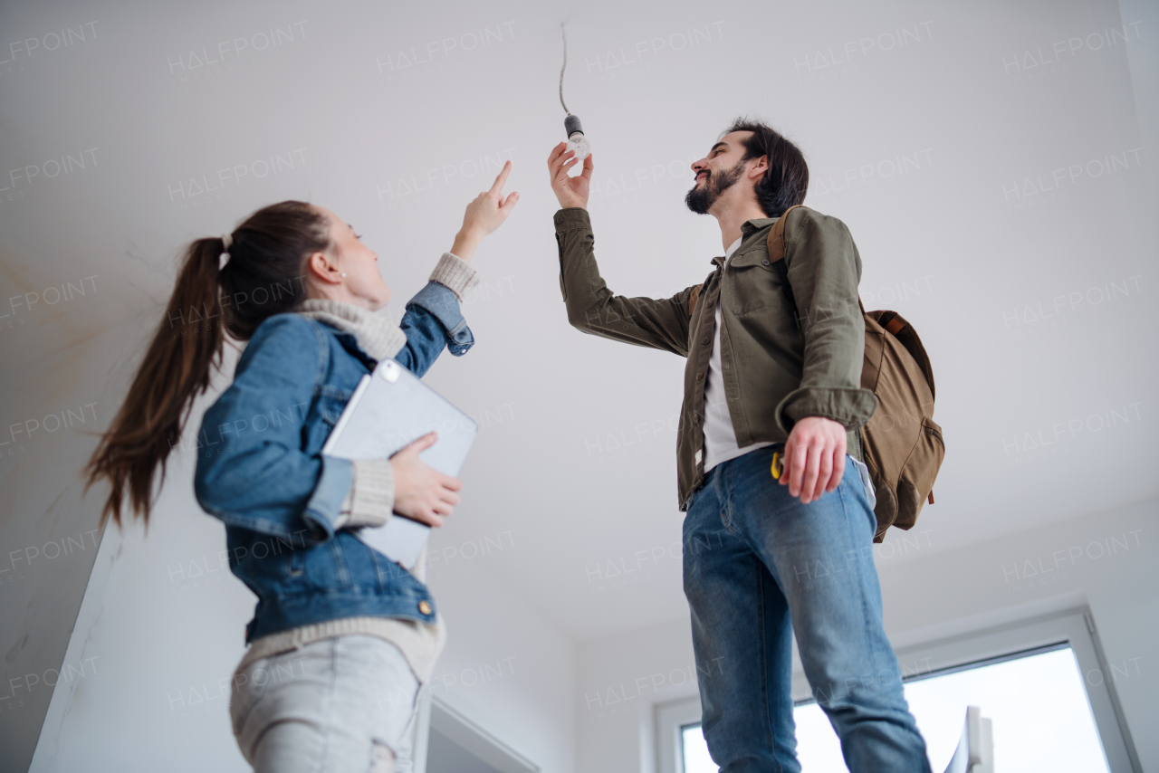 Low angle view of young couple with talbet moving and planning in new flat, new home and relocation concept.