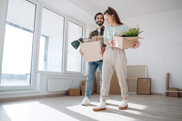 Happy young couple with boxes moving in new flat, new home and relocation concept.