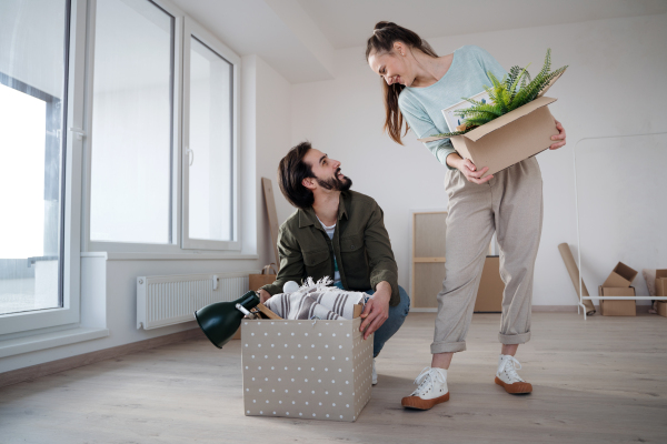 Happy young couple with boxes moving in new flat, new home and relocation concept.