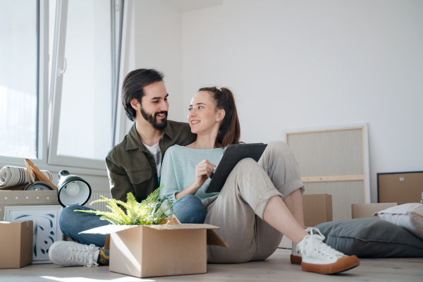 Happy young couple with boxes moving in new flat, new home and relocation concept.