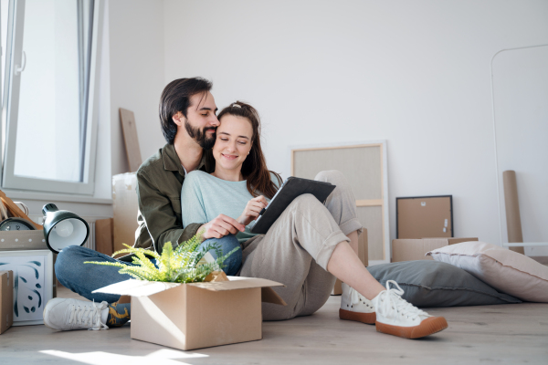 Happy young couple with boxes moving in new flat, new home and relocation concept.