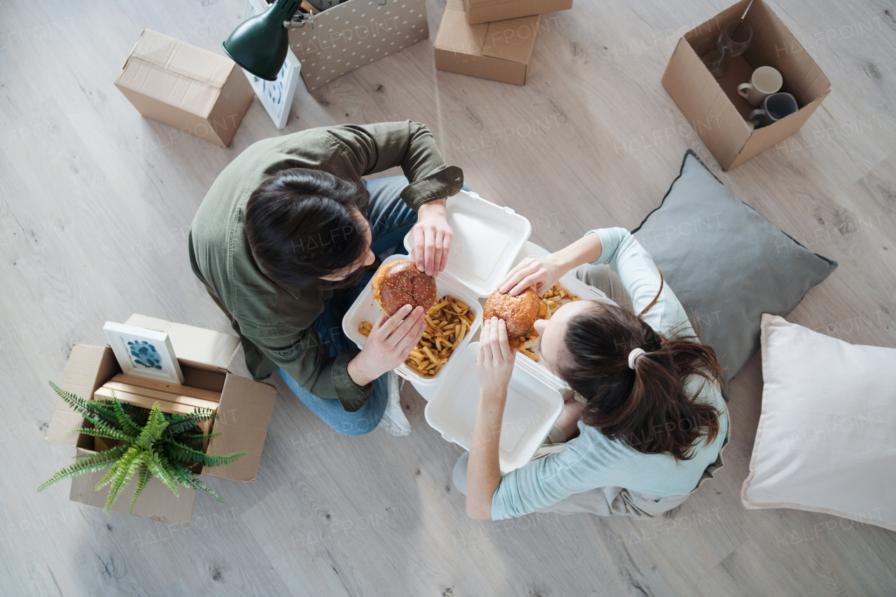 Top view of young couple with hamburgers and boxes moving in new flat, new home and relocation concept.