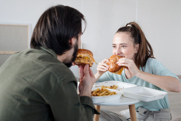 Young couple with hamburgers and boxes moving in new flat, new home and relocation concept.