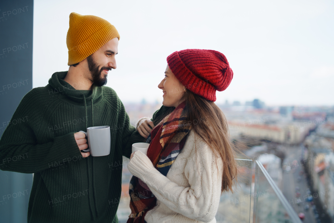 Happy young couple owners with tea on balcony in new flat, moving in, new home and relocation concept.