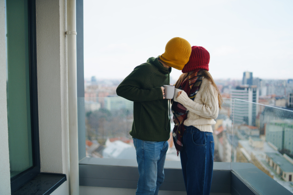 Happy young couple owners with coffee on balcony in new flat, moving in, new home and relocation concept.