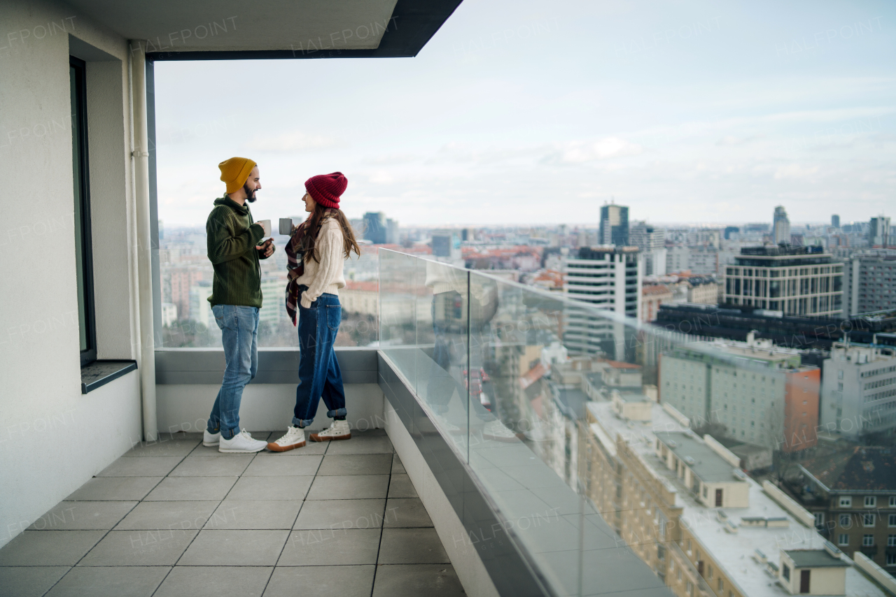 Happy young couple owners with coffee on balcony in new flat, moving in, new home and relocation concept.