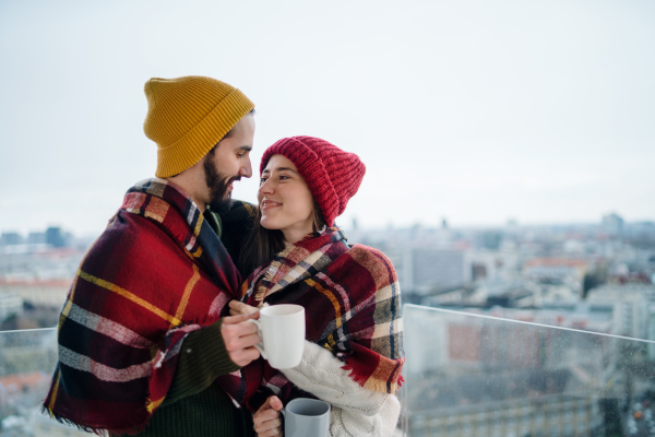 Happy young couple owners with coffee on balcony in new flat, moving in, new home and relocation concept.