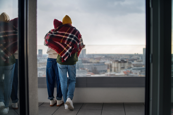 A rear view of young couple owners on balcony in new flat, moving in, new home and relocation concept.