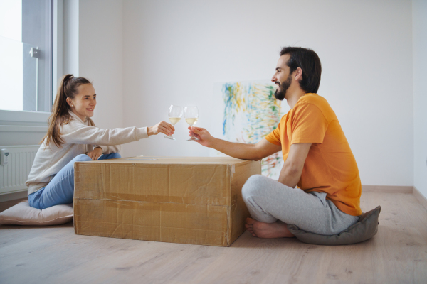 Happy young couple with boxes and wine moving in new flat, new home and relocation concept.