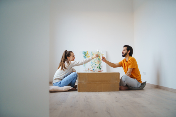 Happy young couple with boxes and wine moving in new flat, new home and relocation concept.