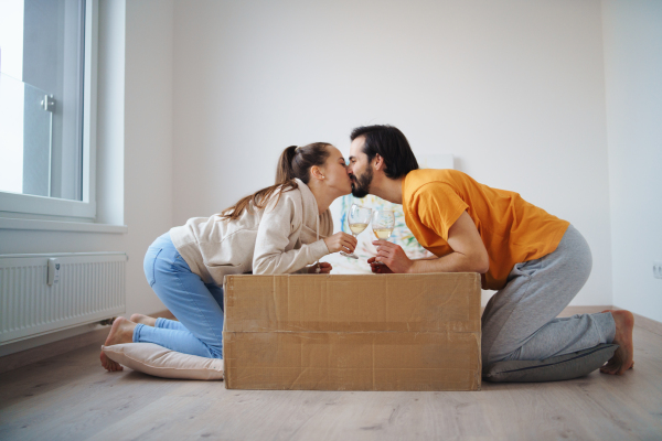 Happy young couple with boxes and wine moving in new flat, new home and relocation concept.