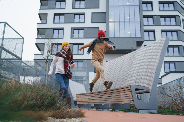 Low angle view of cheerful young couple owners jumping outdoors in front of new flat, new home and relocation concept.