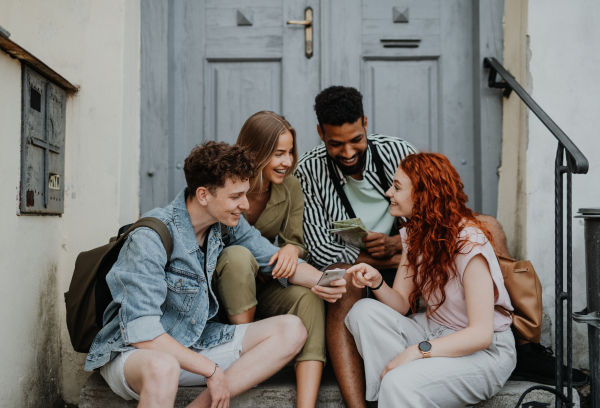 Portrait of group of young people outdoors on trip in town, using map.