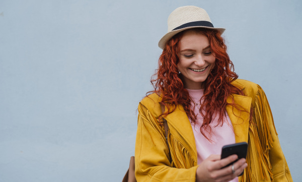 A young woman tourist outdoors against white background on trip in town, using smartphone.