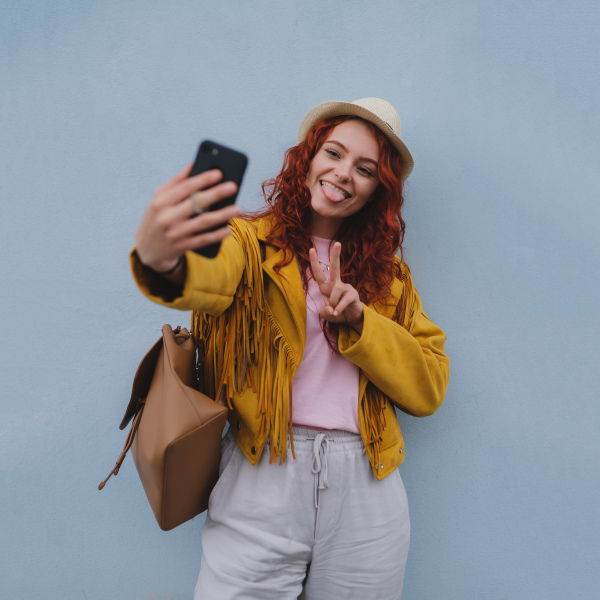 A young woman tourist outdoors against white background on trip in town, taking selfie.