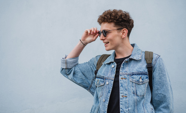 A happy young man tourist outdoors against white background on trip in town, looking aside.