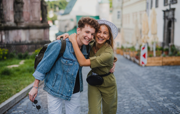 A happy young couple outdoors on street on town trip, walking and looking at camera.