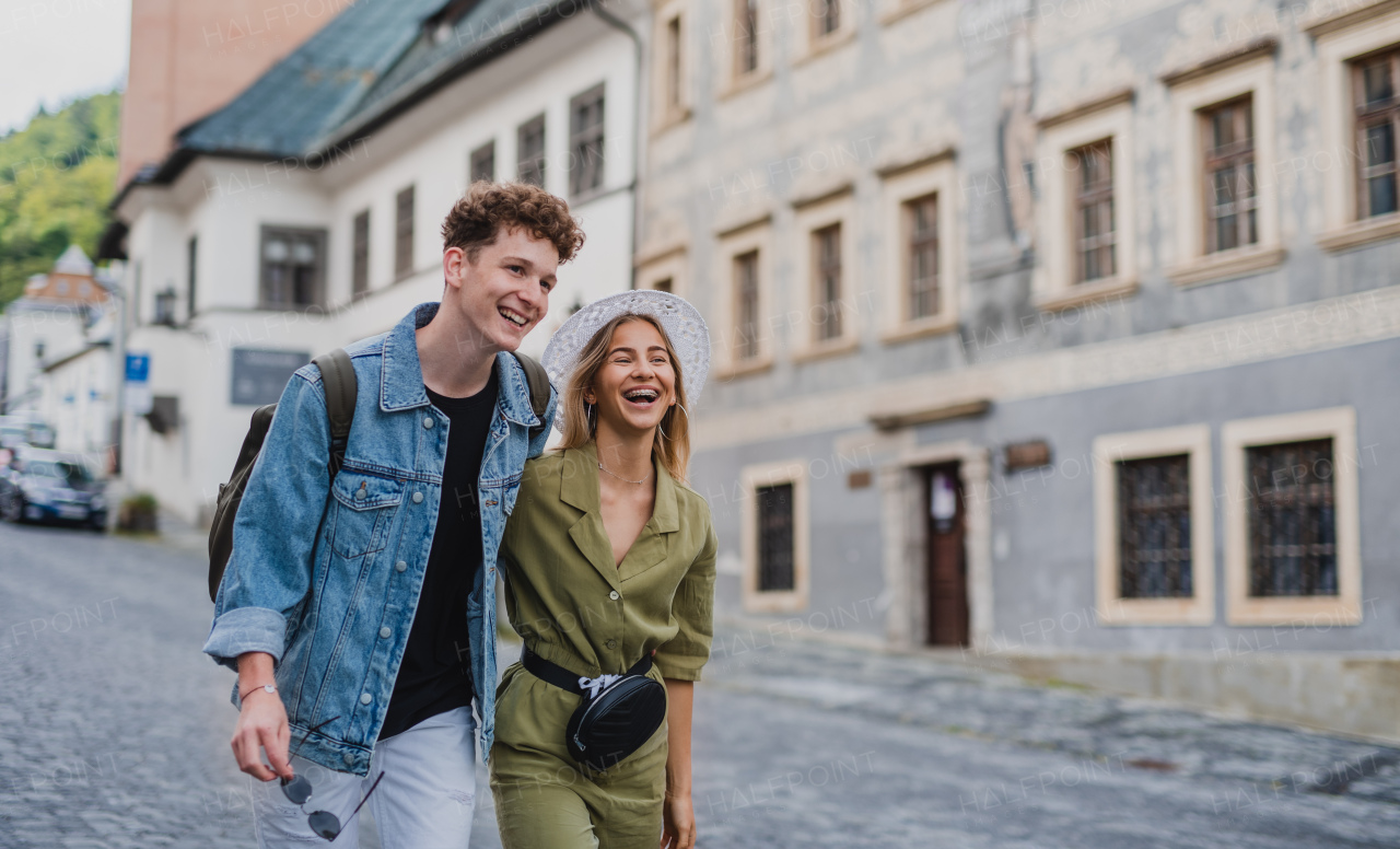 A happy young couple outdoors on street on town trip, walking and talking.