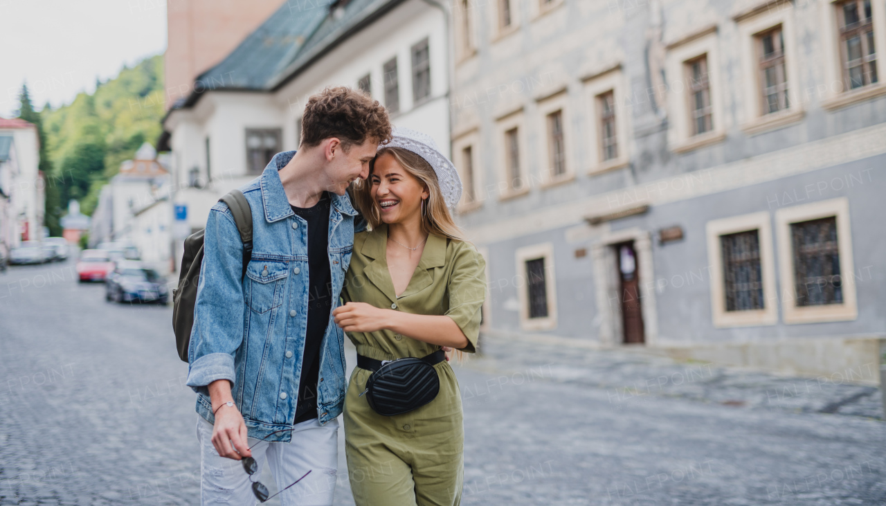 A happy young couple outdoors on street on town trip, walking and talking.