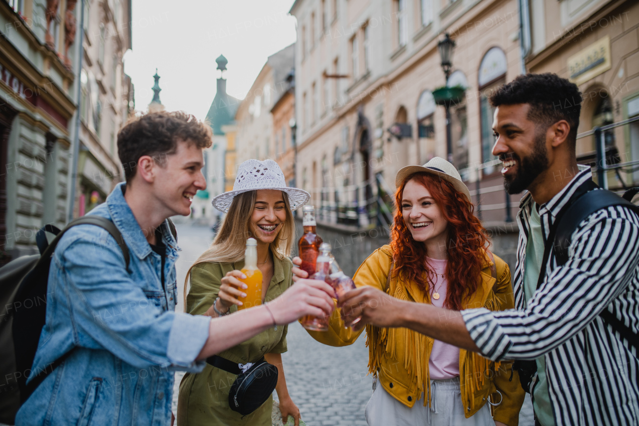 A front view of group of happy young people with drinks outdoors on street on town trip, laughing.