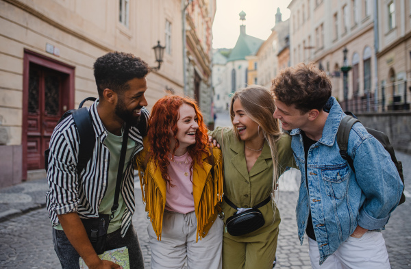 A front view of group of happy young people outdoors on street on town trip, having fun.